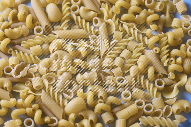 Different pasta types on light blue background