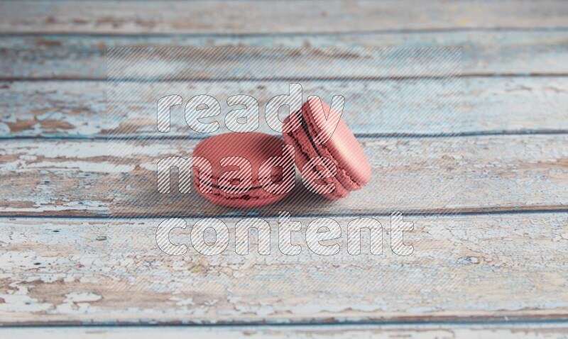 45º Shot of two Pink Raspberry macarons on light blue wooden background