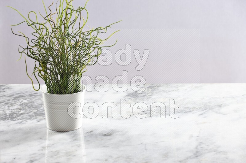Green artificial plant in white pot on light grey marble background
