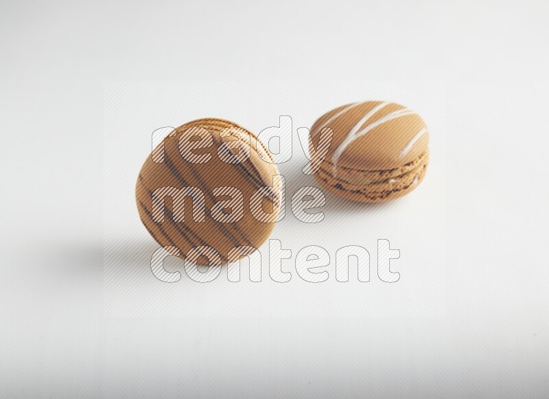 45º Shot of of two assorted Brown Irish Cream, and light brown  Almond Cream macarons on white background