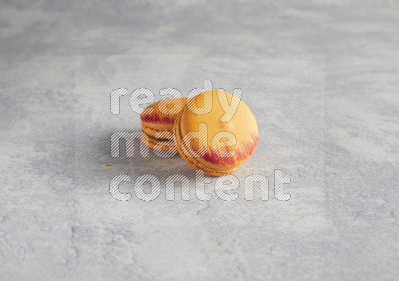 45º Shot of two orange Exotic macarons on white  marble background