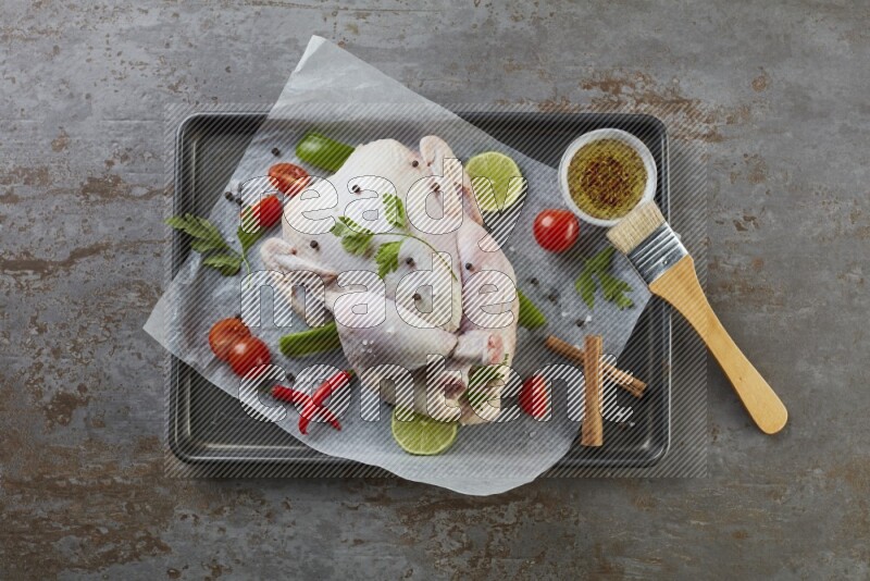whole raw chicken on an oven trey direct on a rustic grey background