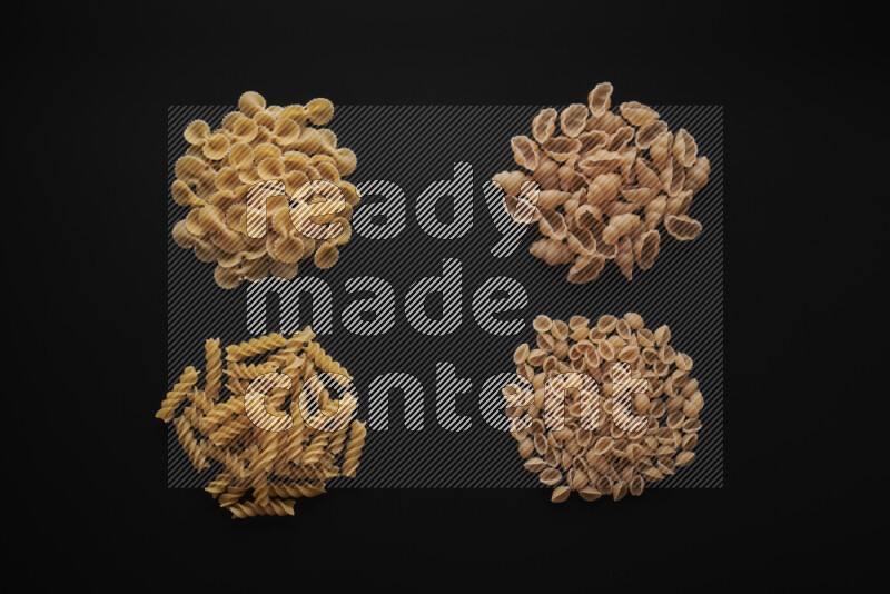 Different pasta types in bunches on black background