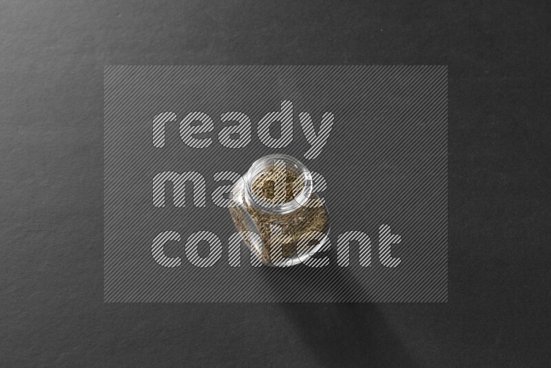 كمون في وعاء زجاجي علي خلفية سوداء