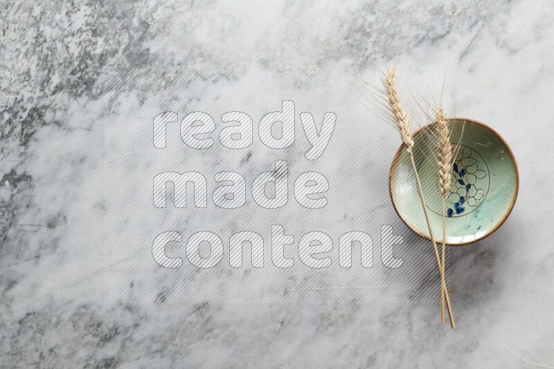 Wheat stalks on decorative pottery plate on grey marble background