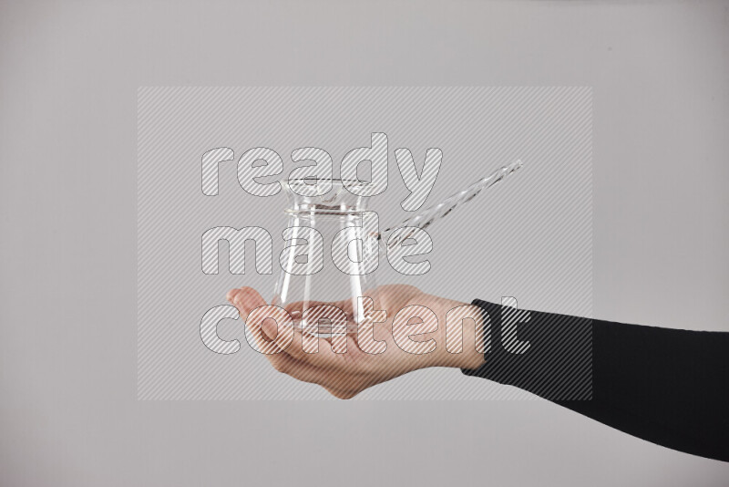 A woman in black abaya holding different glassware in different positions