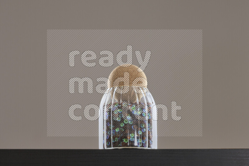 Sequins in a glass jar on black background