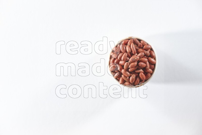 A beige ceramic bowl full of red skin peanuts on a white background in different angles