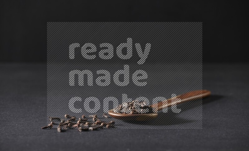 حبوب القرنفل في ملعقة خشبية علي خلفية سوداء