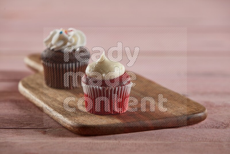 Red velvet mini cupcake topped with cream on a wooden board
