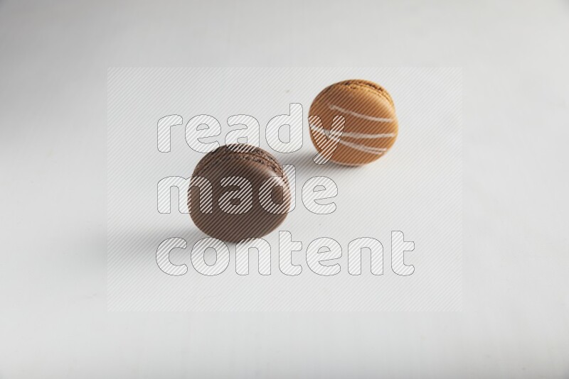 45º Shot of of two assorted Brown Irish Cream, and Brown Dark Chocolate macarons on white background