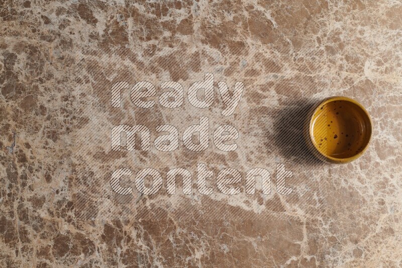 A multicolored pottery bowl on beige marble background