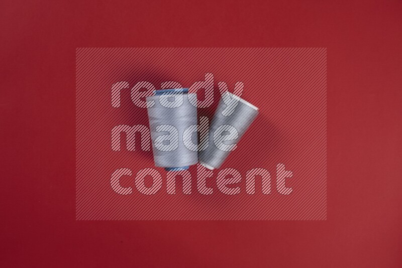 مجموعة من أدوات الخياطة والتفصيل رمادية اللون على خلفية حمراء