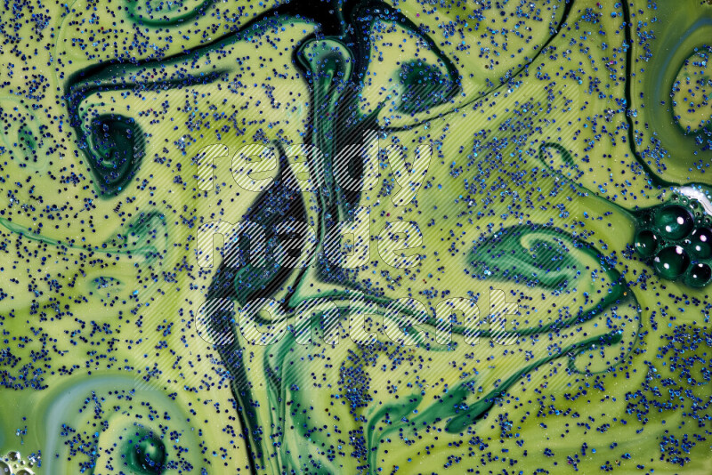 A close-up of sparkling blue glitter scattered on swirling blue and green background