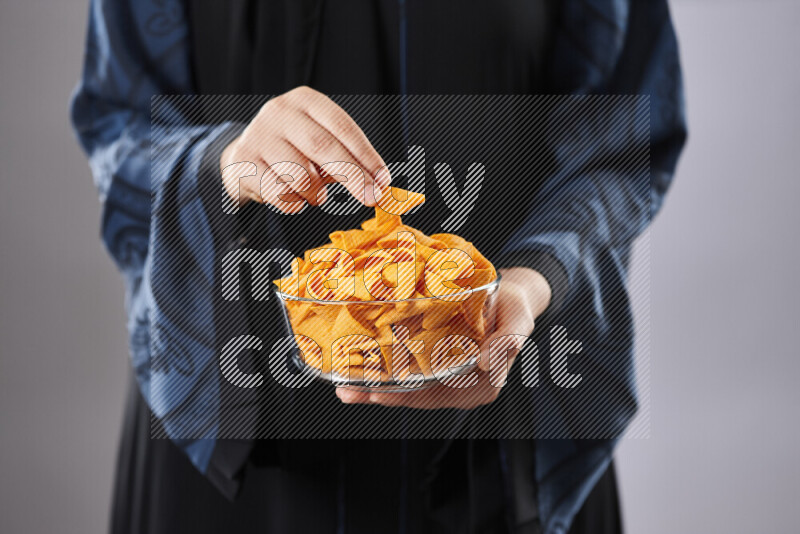 Woman in abaya holding different kinds of snacks in different positions