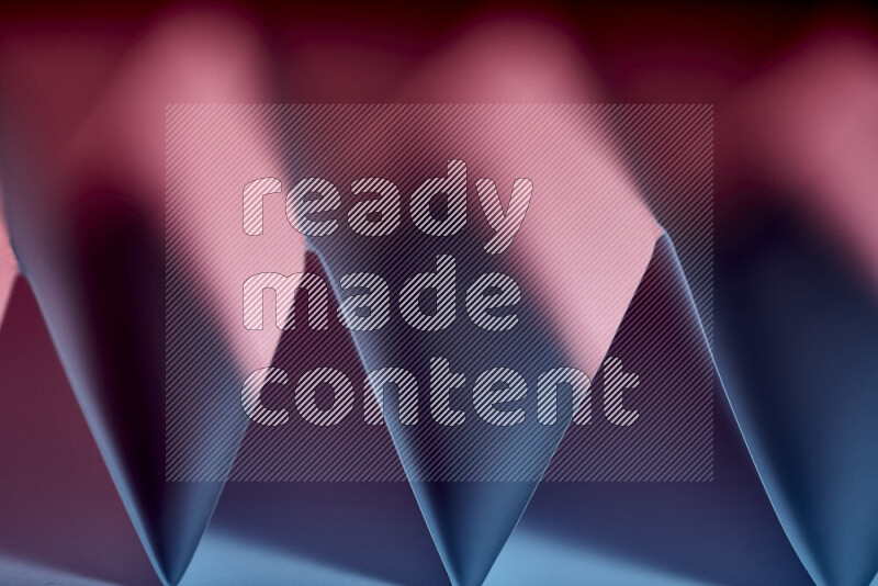 A close-up abstract image showing sharp geometric paper folds in blue and red gradients