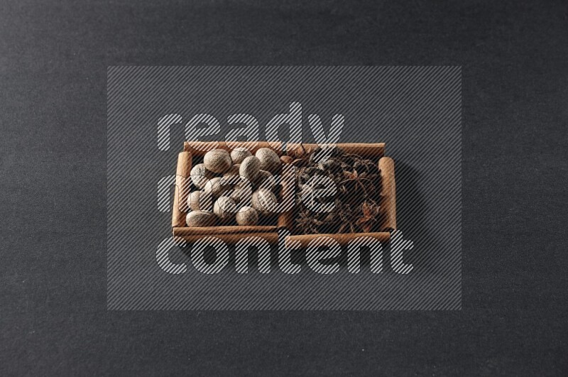 مربعان من أعواد القرفة ممتلئان بجوزة الطيب واليانسون النجمي علي خلفية سوداء