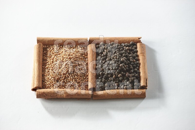 2 squares of cinnamon sticks full of mustard seeds and black peppers on white flooring