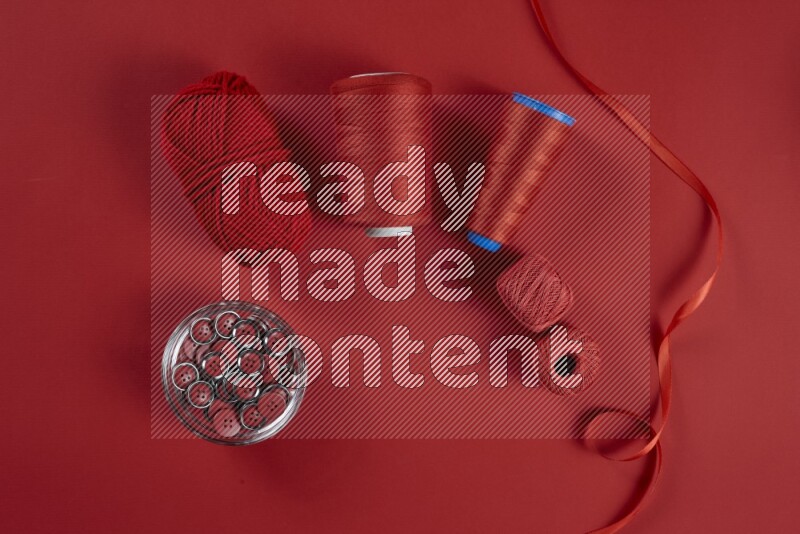 A red collection of sewing and tailoring tools arranged on a red background