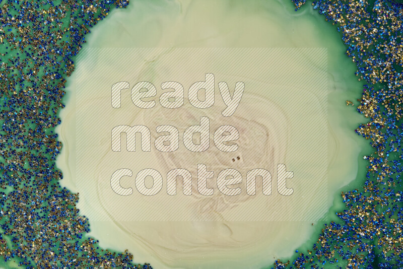 A close-up of sparkling blue glitter scattered on swirling blue and green background