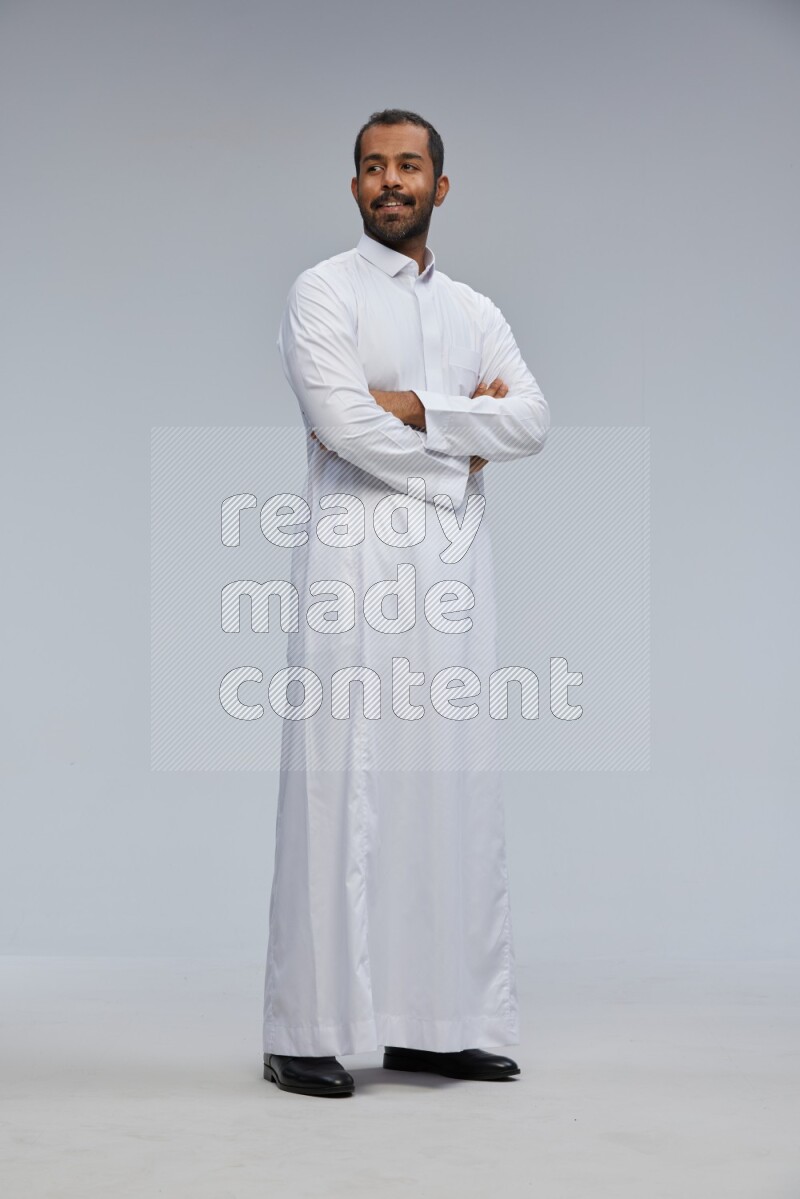 Saudi man wearing Thob standing with crossed arms on Gray background