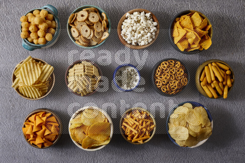 Assorted snacks in pottery bowls on grey background