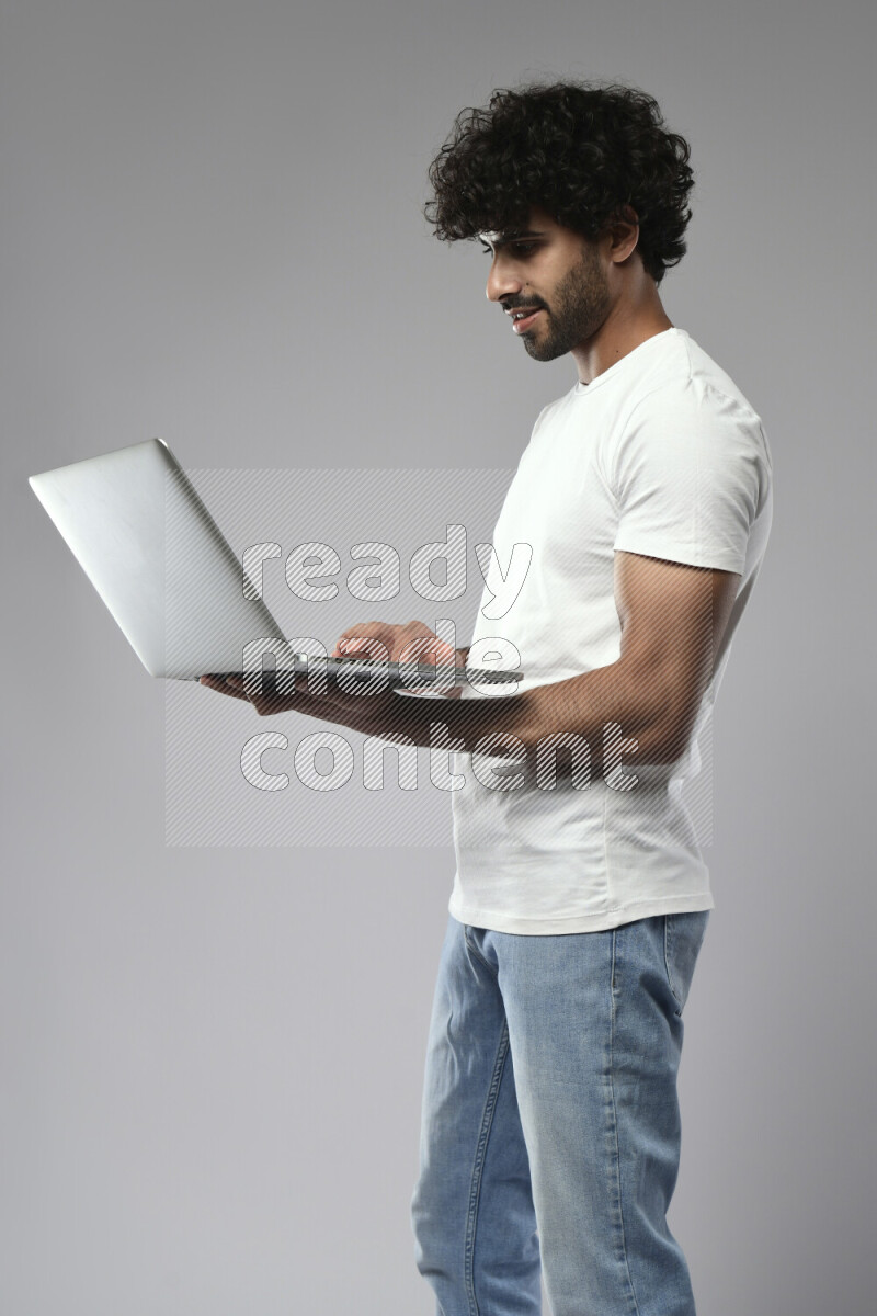 A man wearing casual standing and working on a laptop on white background