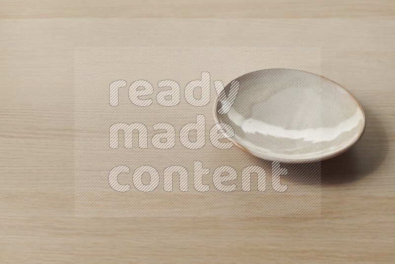 A beige pottery plate on light wooden background