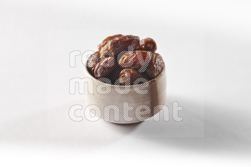 Dates in a beige pottery bowl on white background