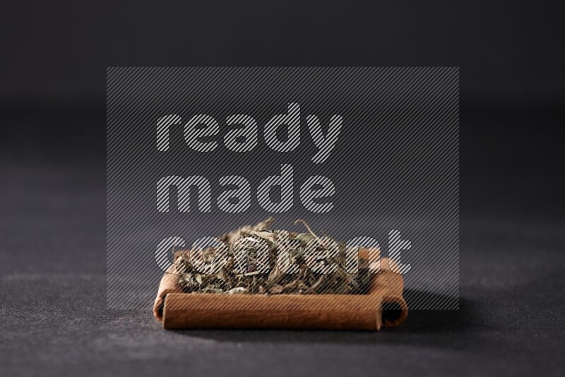 A single square of cinnamon sticks full of dried basil on black flooring