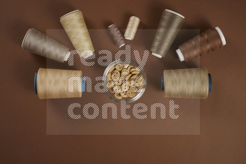 A brown collection of sewing and tailoring tools arranged on a brown background
