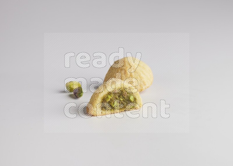 Two Pieces of Maamoul filled with pistachio paste  one of them is cut direct on white background