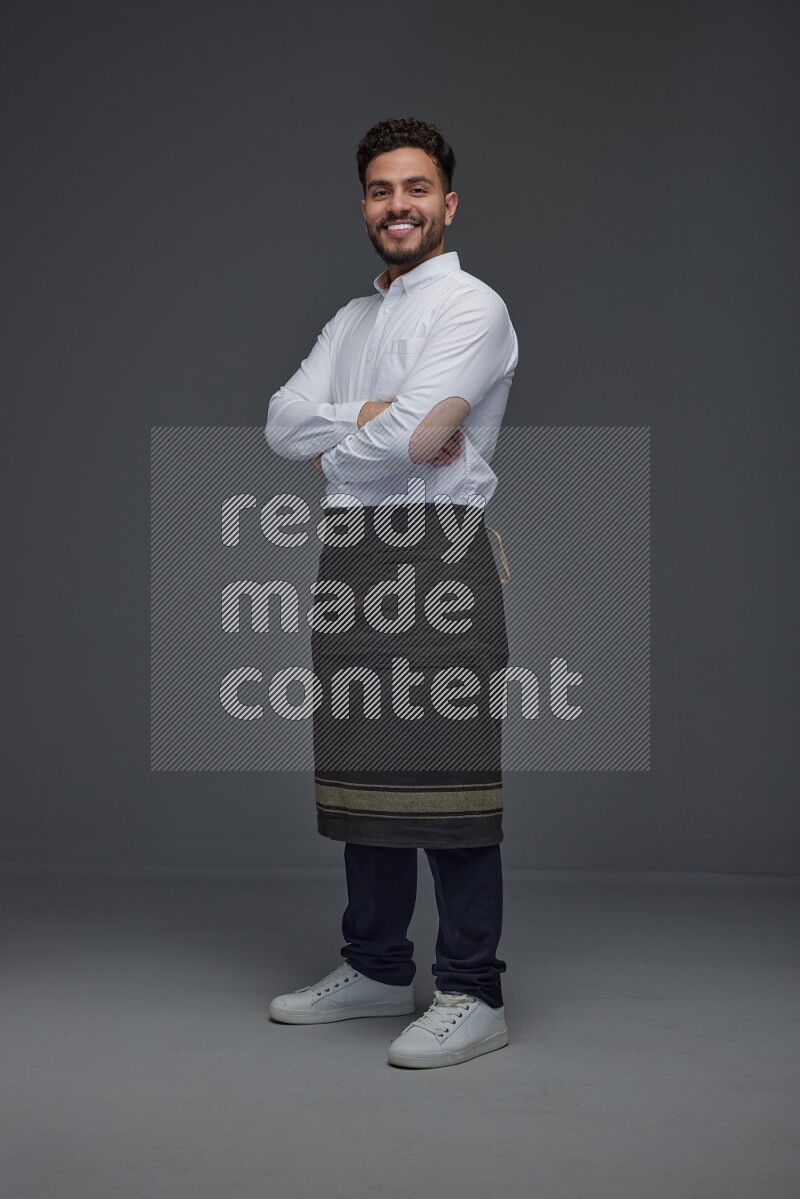 A man wearing smart casual and apron standing and making multi poses eye level on a gray background