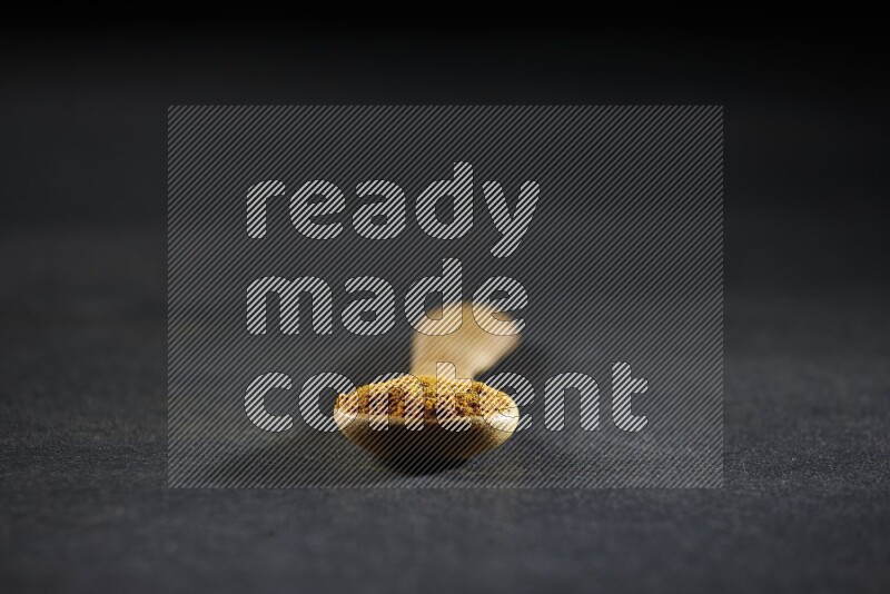 ملعقة خشبية ممتلئة ببودرة الكركم على خلفية سوداء