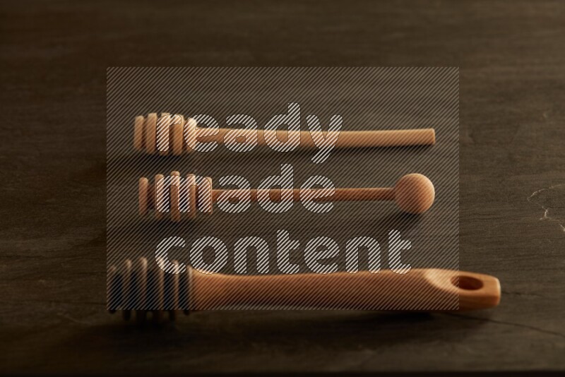 Wooden honey dipper on black slate background