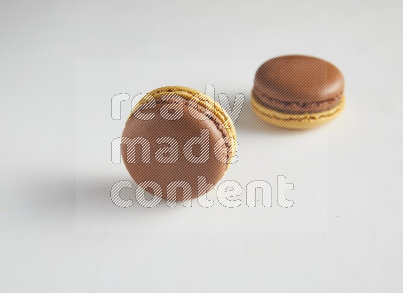 45º Shot of two Yellow and Brown Chai Latte macarons on white background