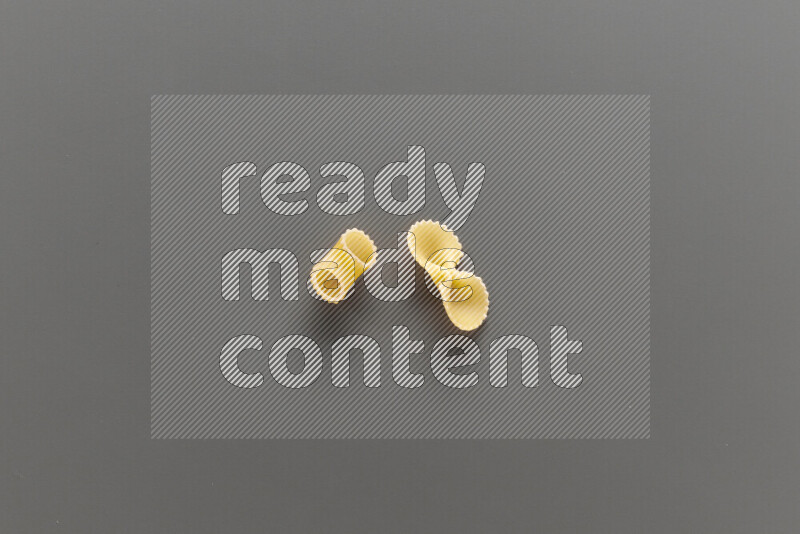 Elbow pasta with other types of pasta on grey background