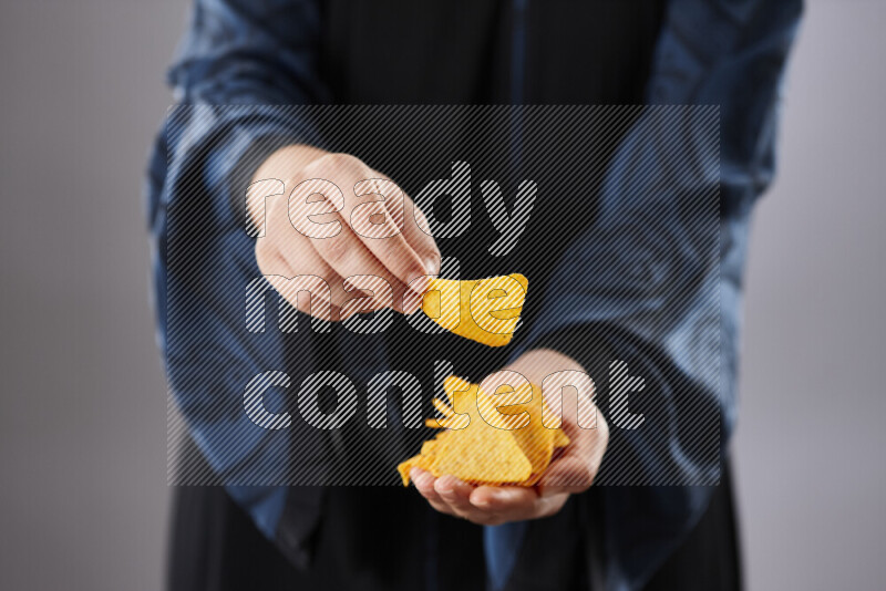 Woman in abaya holding different kinds of snacks in different positions