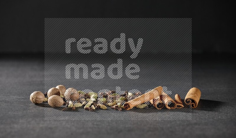 Cardamom, cloves, nutmeg and cinnamon sticks on black flooring