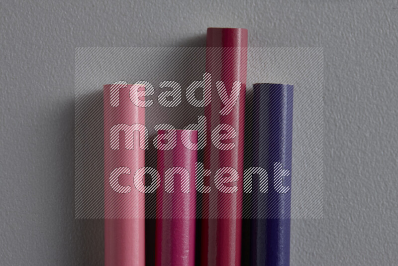 A collection of sharpened colored pencils arranged showcasing a gradient of pink and purple hues on grey background