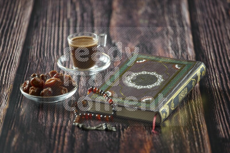 Quran with dates, prayer beads and different drinks all placed on wooden background