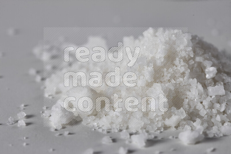 A bunch of coarse sea salt crystals on white background