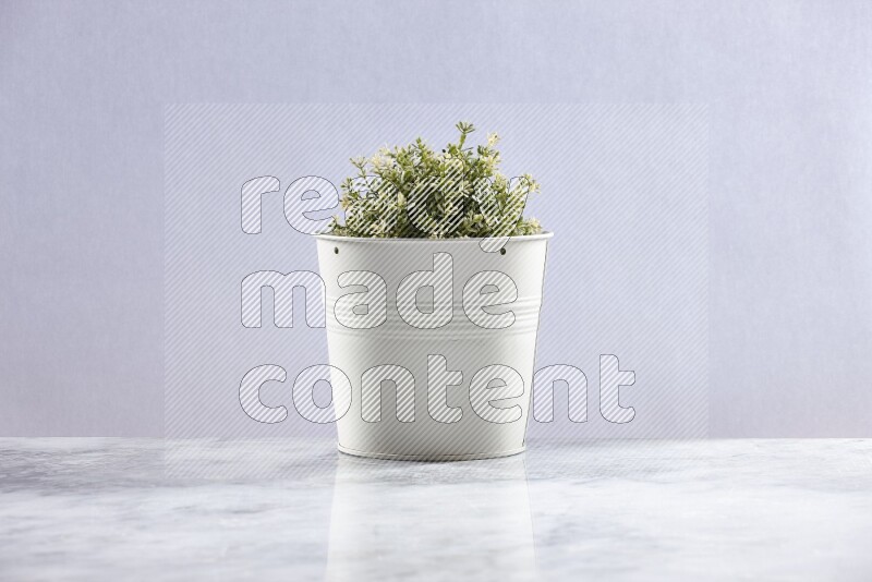 Artificial plant in white pot on grey marble background