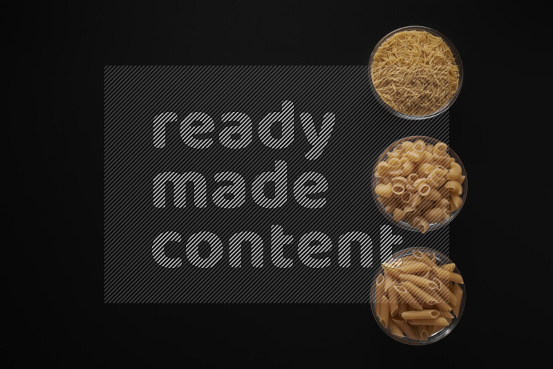 Different pasta types in 3 glass bowls on black background
