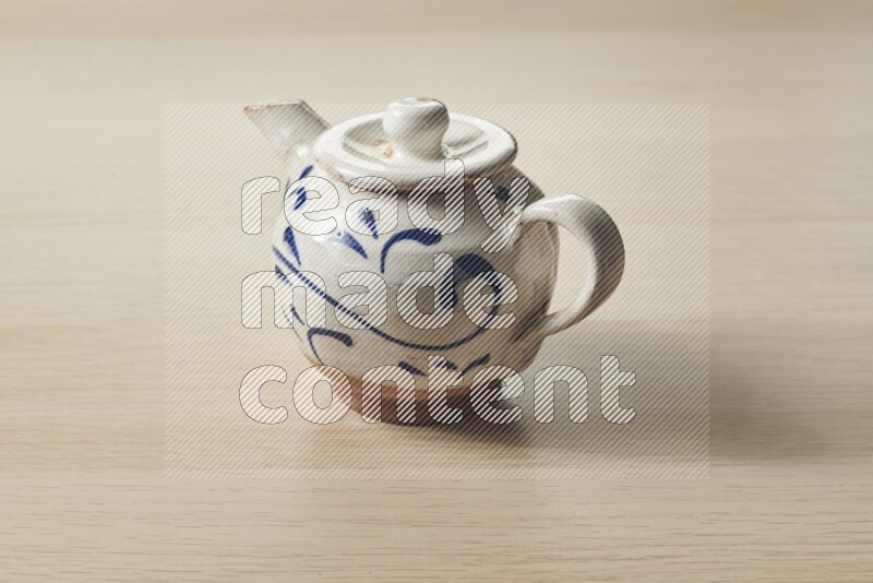 A pottery teapot on light wooden background
