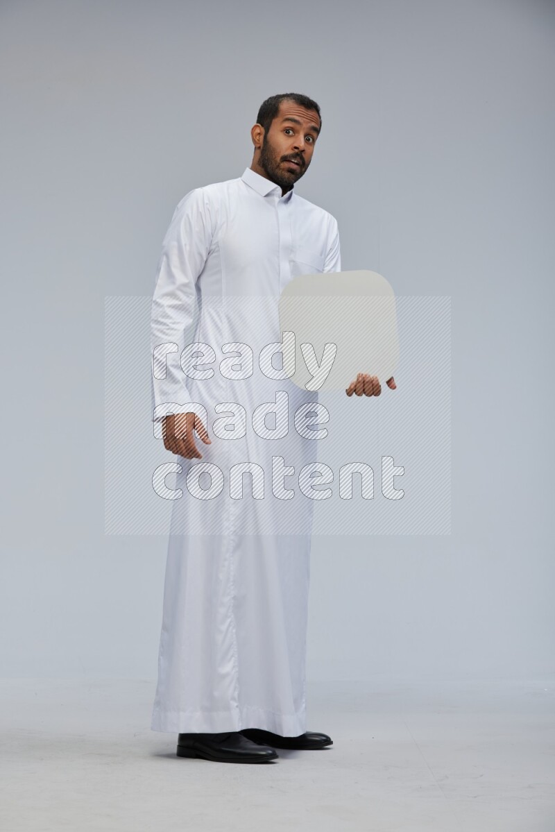 Saudi man wearing Thob standing holding social media sign on Gray background
