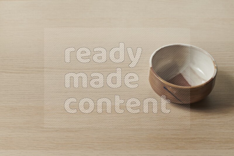 A multicolored pottery bowl on light wooden background