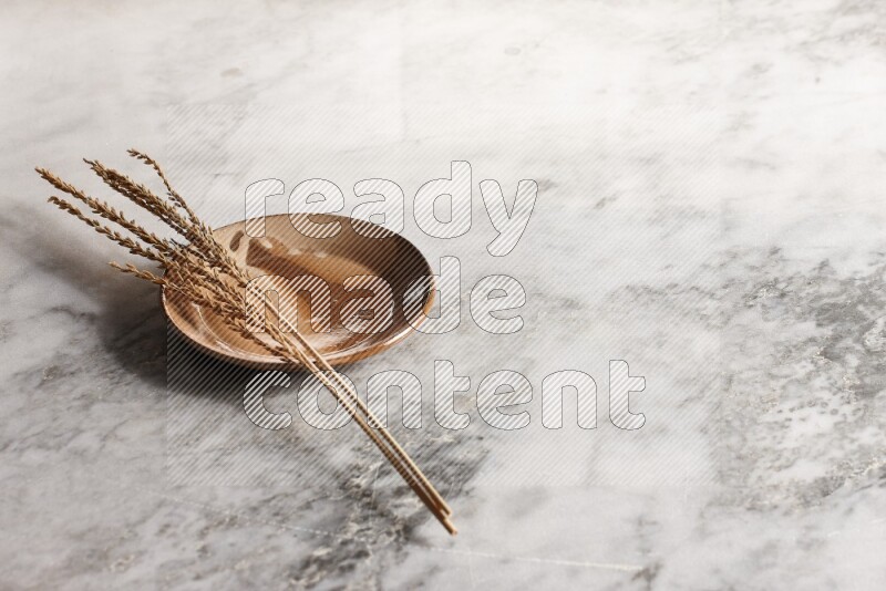 Wheat stalks on multicolored pottery plate on grey marble background