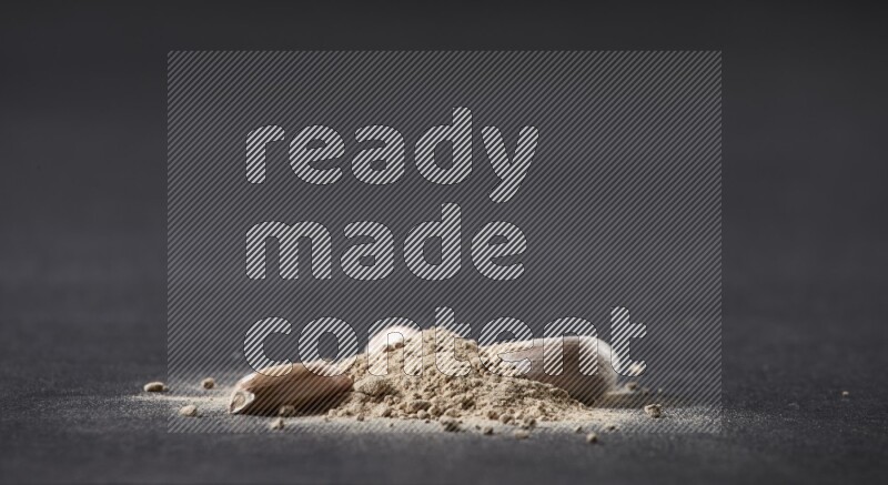 A small pile of garlic powder with some of cloves and a whole garlic bulb on a black flooring