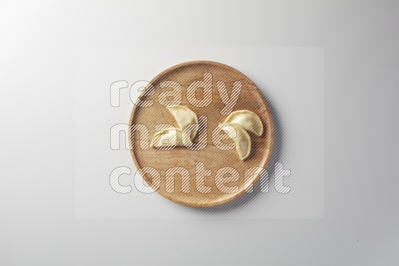 Four Sambosas on a wooden round plate on a white background